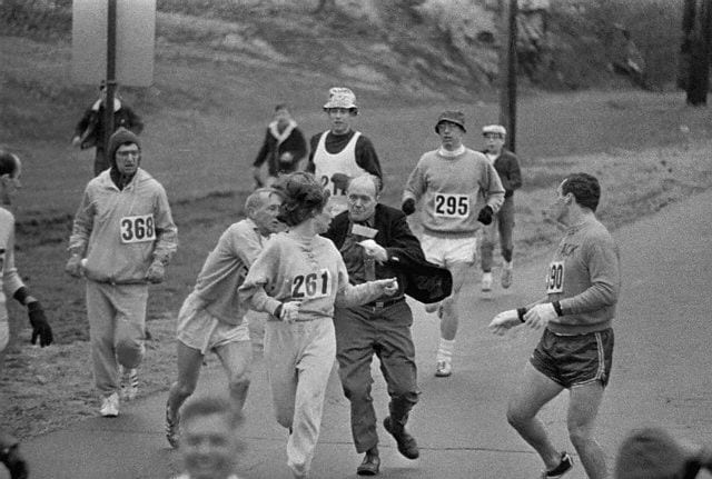 19 Apr 1967, Hopkinton, Massachusetts, USA --- The rule that no women shall run in the Boston Athletic Association (BAA) Marathon is being put to a very real test in this photo. Trainer Jack Semple (in street clothes) enters the field of runners to try to pull Kathy Switzer (261) out of the race. Male runners move in to form protective curtain around the female track hopeful, until the protesting trainer is finally wedged out of the race, and the lady is allowed to finish the marathon. --- Image by © Bettmann/CORBIS