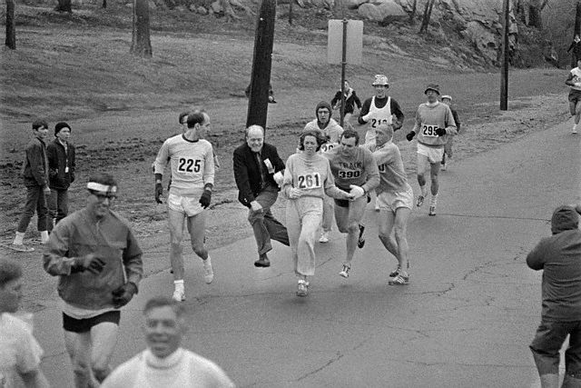 19 Apr 1967, Hopkinton, Massachusetts, USA --- In the Boston Marathon, one of two women running in the normally all-male-race, Kathy Switzer, (261) of Syracuse, New York, is being hassled by BAA Marathon Director Bill Cloney, as he attempted to stop her from competing. The dark-haired girl did not show up for the physical examination required of all starters, (had she appeared at the starting line, she would never have been allowed to compete). she remained in the race, but was never seen near the finish line. --- Image by © Bettmann/CORBIS