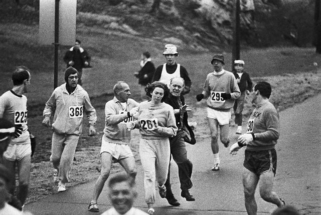 19 Apr 1967, Hopkinton, Massachusetts, USA --- Trainer Jock Semple -- in street clothes -- enters the field of runners (left) to try to pull Kathy Switzer (261) out of the race. Male runners move in to form a protective curtain around female track hopeful until the protesting trainer is finally wedged out of the race --- Image by © Bettmann/CORBIS