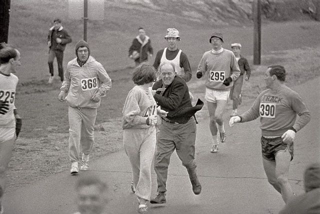 19 Apr 1967, Hopkinton, Massachusetts, USA --- The rule that no women shall run in the Boston Athletic Association (BAA) Marathon is being put to a very real test in this photo. Trainer Jack Semple (in street clothes) enters the field of runners to try to pull Kathy Switzer (261) out of the race. Male runners move in to form protective curtain around the female track hopeful, until the protesting trainer is finally wedged out of the race, and the lady is allowed to finish the marathon. --- Image by © Bettmann/CORBIS
